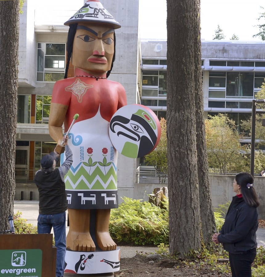 FILE - In this Oct. 2, 2019 file photo Carver Greg Colfax and Evergreen graduate Bunni Peterson-Haitwas unveil the restored &quot;Welcome Woman&quot; carving during a ceremony at the entrance to Red Square on the campus of The Evergreen State College in Olympia, Wash. In hopes of ending enrollment woes, The Evergreen State College in Olympia, is overhauling its academic programs and installing more structure to the school&#039;s alternative structure.