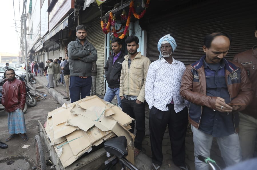 Daily laborers wait outside a market which was the scene of a devastating fire Sunday, in New Delhi, India, Monday, Dec. 9, 2019. Authorities say an electrical short circuit appears to have caused a devastating fire that killed dozens of people in a crowded market area in central New Delhi. Firefighters fought the blaze from 100 yards away because it broke out in one of the area&#039;s many alleyways, tangled in electrical wire and too narrow for vehicles to access.