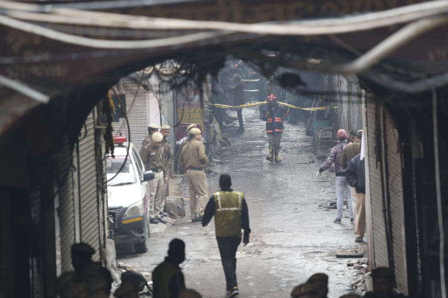 Police officers cordon off the site of a fire in a narrow lane in New Delhi, India, Sunday.