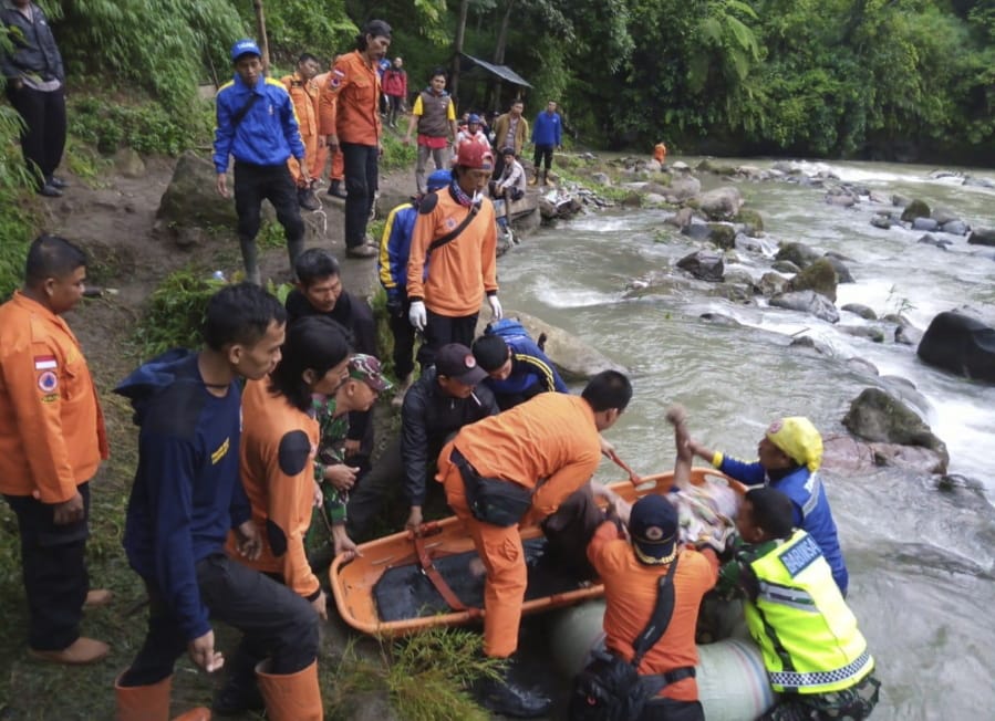 In this photo released by the National Search And Rescue Agency (BASARNAS), rescuers remove the body of a victim of a bus accident in Pagaralam, Indonesia, Tuesday, Dec. 24, 2019. A number of people were killed when the passenger bus plunged into the ravine on Sumatra island after its brakes apparently malfunctioned, police said Tuesday.