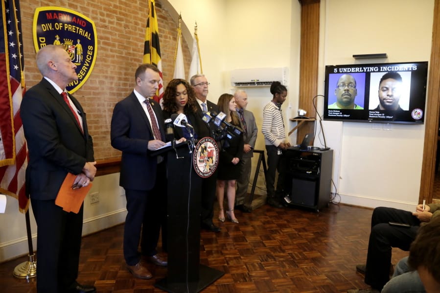 Maryland Assistant State Attorney Patrick Seidel, second from left, stands next to State Attorney Marilyn Mosby, third from right, as a monitor displays two of the correction officers indicted during a news conference, Tuesday, Dec. 3, 2019, in Baltimore. Twenty five correction officers, most of whom were taken into custody earlier in the day, are charged with using excessive force on detainees at state-operated Baltimore pretrial correctional facilities.