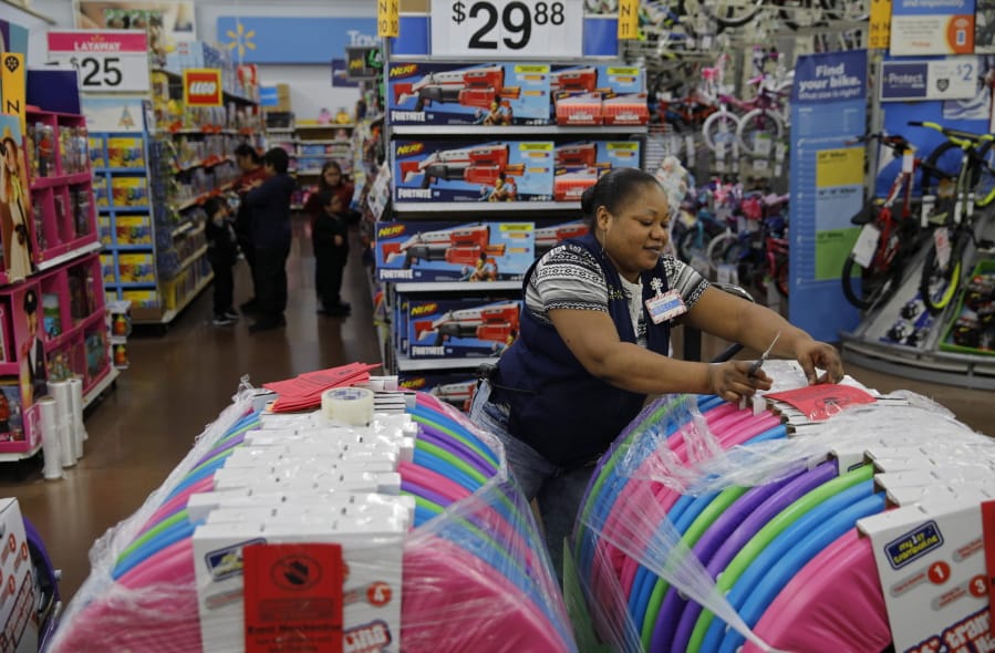 FILE - In this Nov. 27, 2019, file photo Balo Balogun labels items in preparation for a holiday sale at a Walmart Supercenter in Las Vegas. On Friday, Dec. 6, the U.S. government issues the November jobs report.