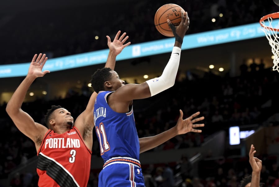 New York Knicks guard Frank Ntilikina, left, drives to the basket on Portland Trail Blazers guard CJ McCollum, right, during the first half of an NBA basketball game in Portland, Ore., Tuesday, Dec. 10, 2019.