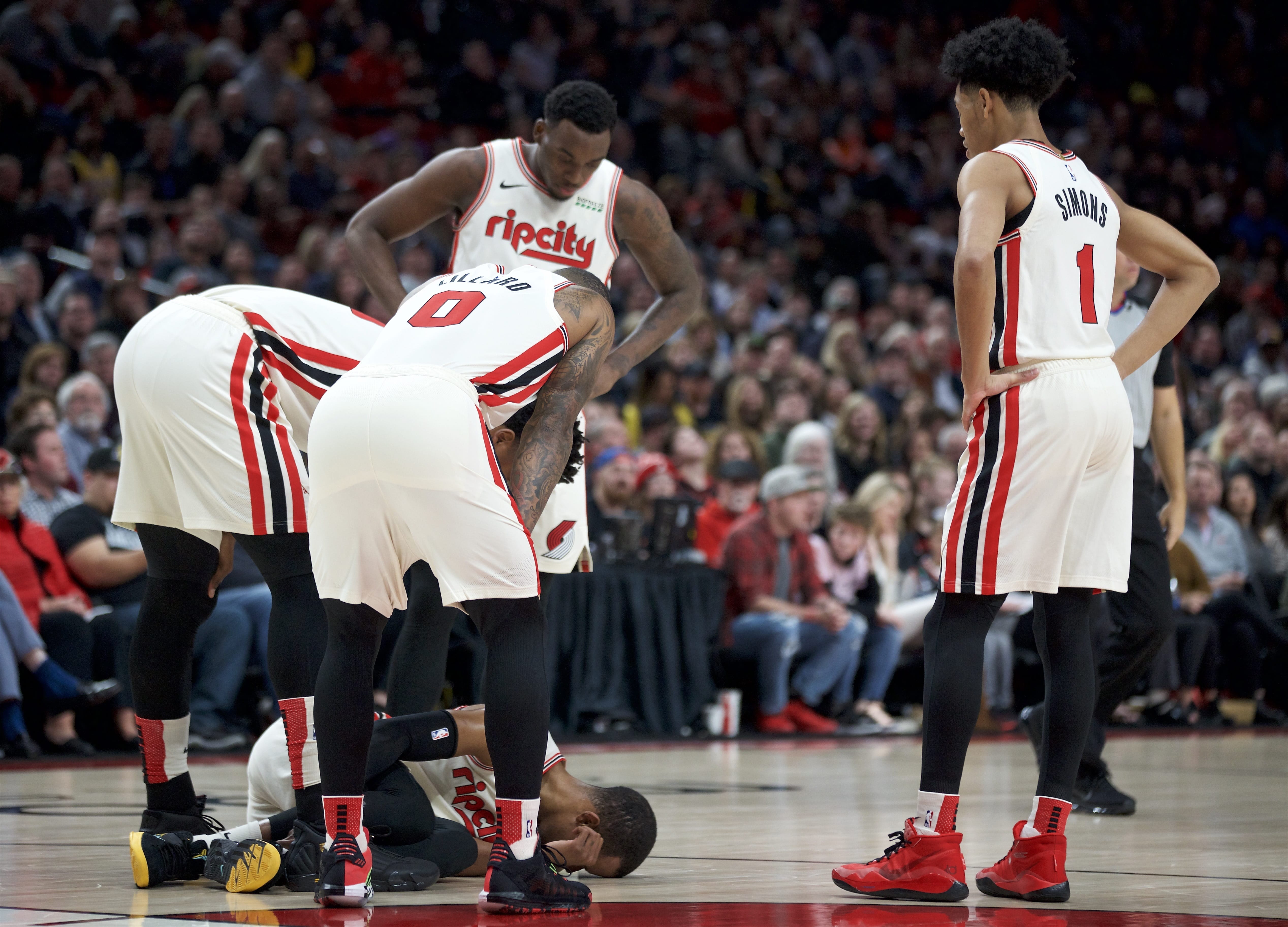 Portland Trail Blazers guard Rodney Hood is surrounded by teammates after tearing his Achilles tendon during the first half of the team's NBA basketball game against the Los Angeles Lakers in Portland, Ore., Friday, Dec. 6, 2019.