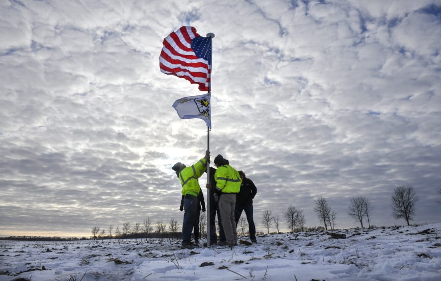 Members of the Krippner family raise a flag Friday, Dec. 6, 2019, in tribute to victims of a Minnesota National Guard Blackhawk helicopter crash that happened on their land near Kimball, Minn. Three soldiers were killed in Thursday&#039;s crash at the edge of a farm field about 30 miles south of St. Cloud. (Dave Schwarz/St.
