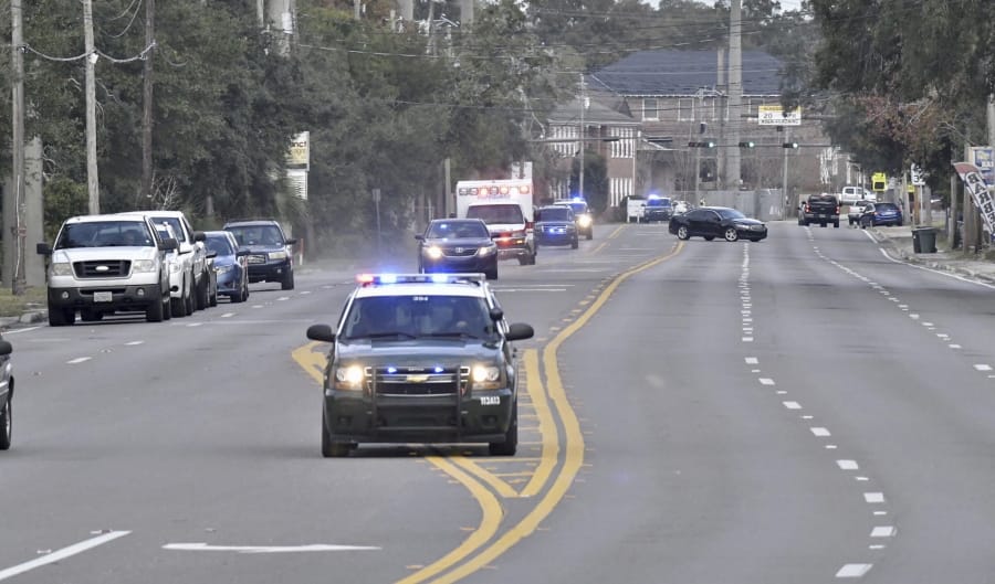 Police cars escort an ambulance after a shooter open fire inside the Pensacola Air Base, Friday, Dec. 6, 2019 in Pensacola, Fla.   The US Navy is confirming that a shooter is dead and several injured after gunfire at the Naval Air Station in Pensacola.