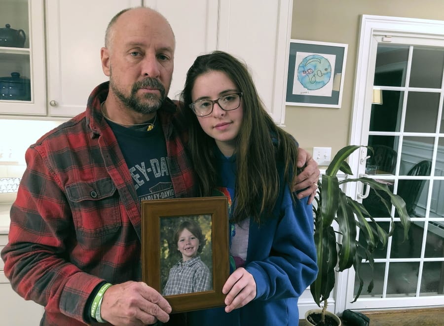 In this Dec. 3, 2019, photo, Mark Barden and his daughter Natalie Barden hold a photograph of Natalie&#039;s late brother, Daniel, at their home in Newtown, Conn. Daniel died in the Dec. 14, 2012, Sandy Hook Elementary School shooting that killed 20 first graders and six educators. Natalie, 17, is among Newtown students who have grown up to become young voices in the gun violence prevention movement.