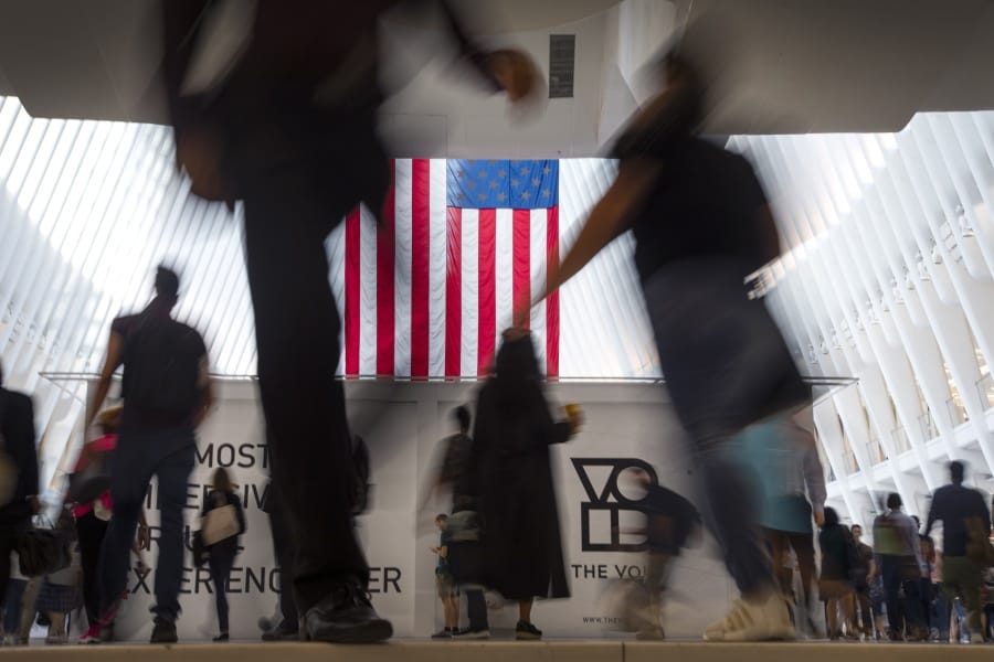 FILE - In this Sept. 11, 2019, photo people walk past an American flag at the start of a work day, at the Oculus, part of the World Trade Center transportation hub in New York. Consumers often worry about losing their personal information in a data breach or to another unknown criminal online. But, family, friends and acquaintances can be the ones stealing and profiting from personal information, creating a tricky and potentially expensive situation for victims to resolve.