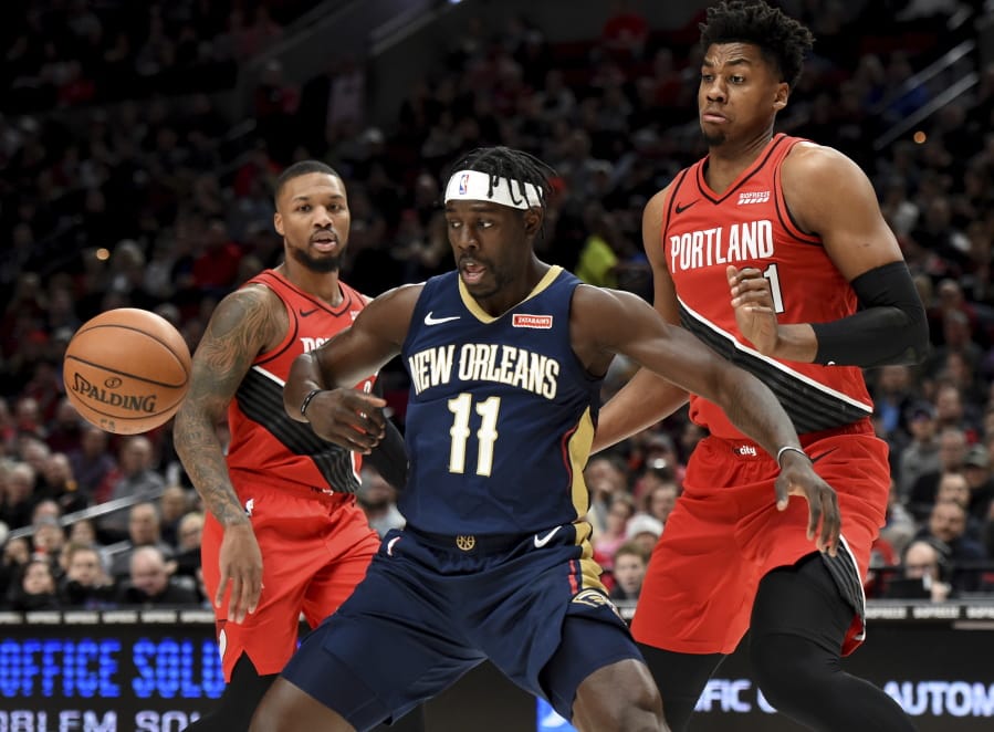 New Orleans Pelicans guard Jrue Holiday, center, loses control of the ball as Portland Trail Blazers guard Damian Lillard, left and center Hassan Whiteside, right, look on during the first half of an NBA basketball game in Portland, Ore., Monday, Dec. 23, 2019. The Blazers won 113-106.