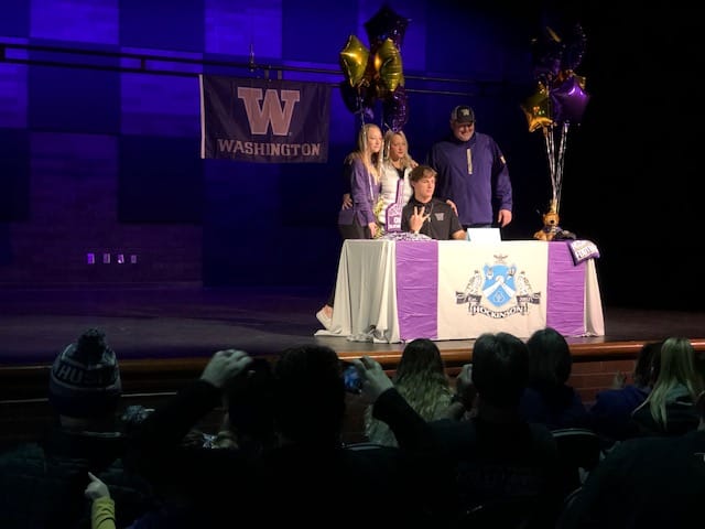 Hockinson's Sawyer Racanelli holds up a "W" while surrounded by his family after signing his National Letter of Intent to the University of Washington on Wednesday at Hockinson's auditorium.