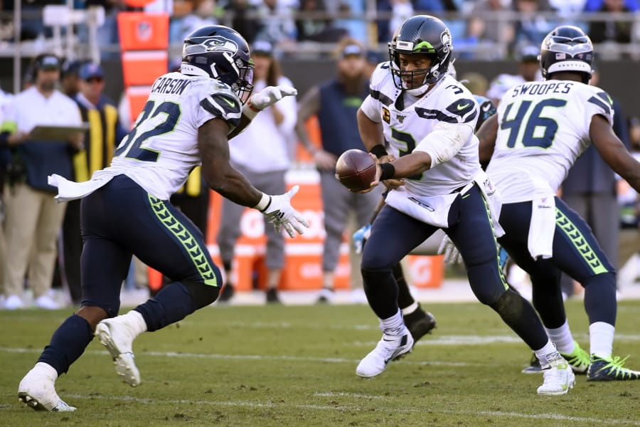 Seattle Seahawks quarterback Russell Wilson (3) hands pff to running back Chris Carson (32) during the second half of an NFL football game against the Carolina Panthers in Charlotte, N.C., Sunday, Dec. 15, 2019.
