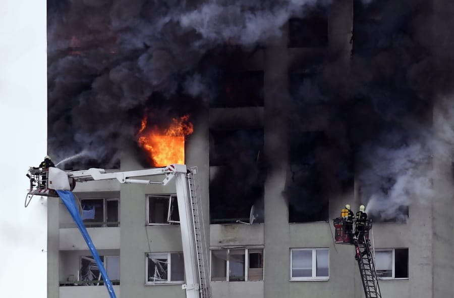 Firefighters on a ladder try to extinguish a fire in a 12-storey apartment block after a gas explosion in Presov, Slovakia, Friday, Dec. 6, 2019. Officials say a gas explosion in an apartment block in Slovakia has killed at least five people and others are trapped on the roof of the building. Firefighters say the explosion occurred in a 12-story building in the city of Presov shortly after noon on Friday.