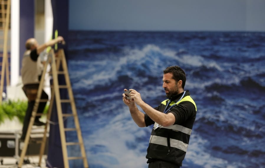 A worker takes a photograph while stands are being set up for the COP25 Climate summit in Madrid, Spain, Sunday, Dec. 1, 2019. This year&#039;s international talks on tackling climate change were meant to be a walk in the park compared to previous instalments. But with scientists issuing dire warnings about the pace of global warming and the need to urgently cut greenhouse gas emissions, officials are under pressure to finalize the rules of the 2015 Paris accord and send a signal to anxious voters.