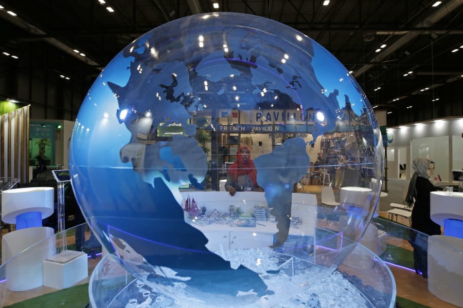 A woman looks at a World globe at the COP25 climate talks congress in Madrid, Spain, Friday, Dec. 13, 2019. Officials from almost 200 countries are scrambling to reach an agreement at a United Nations climate meeting amid growing concerns that key issues may be postponed for another year.