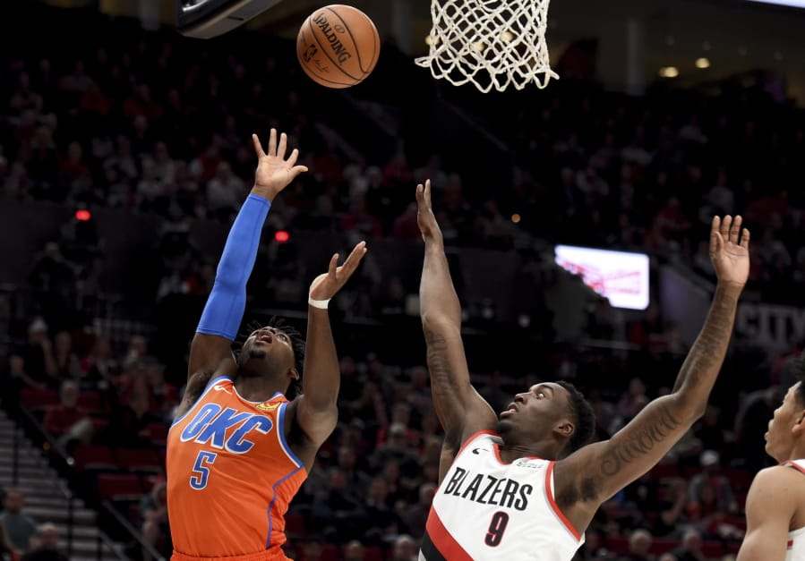 Oklahoma City Thunder guard Luguentz Dort, left, shoots the ball over Portland Trail Blazers forward Nassir Little, right, during the first half of an NBA basketball game in Portland, Ore., Sunday, Dec. 8, 2019.