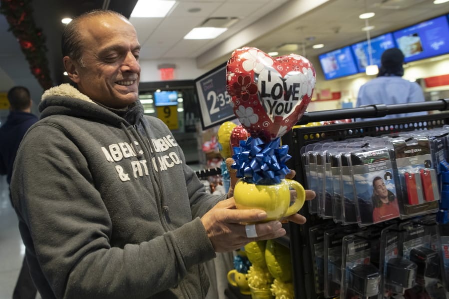 In this Tuesday, Dec. 3, 2019, photo, Mohammed Hafar buys a gift for his daughter Jana Hafar while waiting for her flight at JFK Airport in New York. Jana had been forced by President Donald Trump&#039;s travel ban to stay behind in Syria for months while her father, his wife and son Karim started rebuilding their lives in Bloomfield, N.J., with no clear idea of when the family would be together again. Mohammed was part of a federal lawsuit filed in August of this year over the travel ban waiver process.