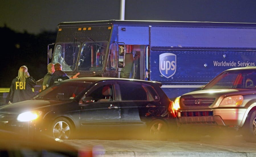 Law enforcement stand near a vehicle that appears to be part of the crime scene where four people were killed, Thursday, Dec. 5, 2019 in Miramar, Fla. The FBI says four people, including a UPS driver, were killed after robbers stole the driver&#039;s truck and led police on a chase that ended in gunfire at a busy Florida intersection during rush hour.