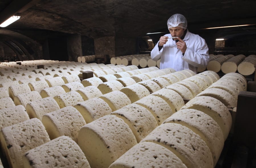 Bernard Roques, a refiner of Societe company, smells a Roquefort cheese as they mature in a cellar in Roquefort, southwestern France. The Trump administration is proposing tariffs on up to $2.4 billion worth of French imports.