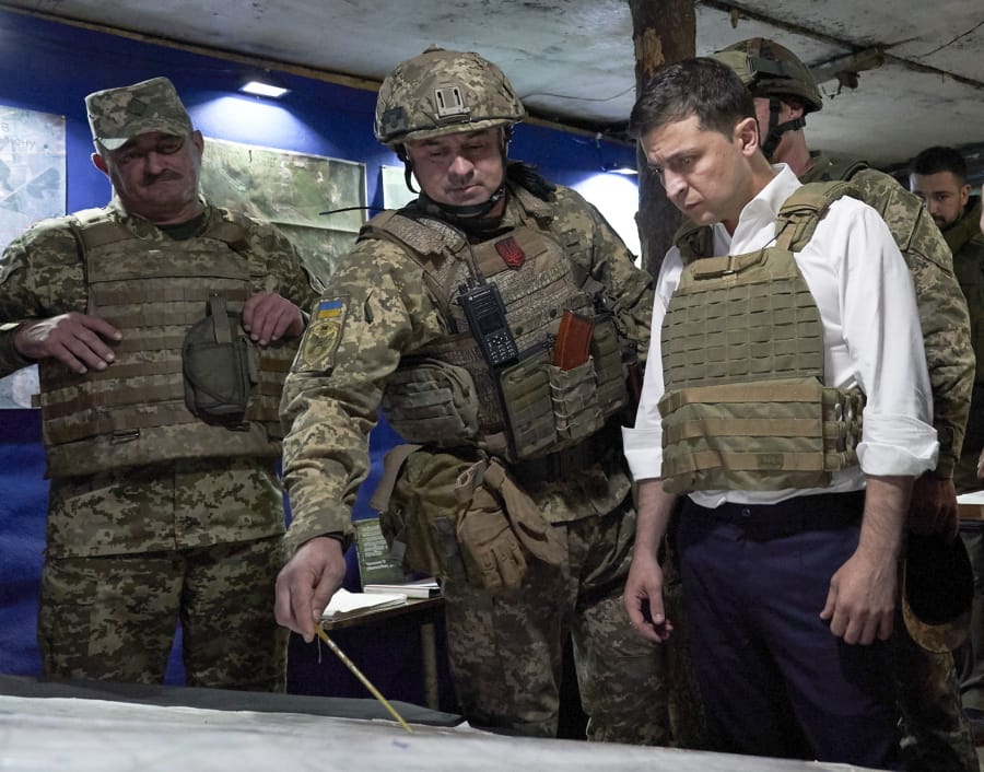 FILE - In this Oct. 14, 2019, file photo, Ukrainian President Volodymyr Zelenskiy, right, listens to a serviceman as he visits the war-hit Donetsk region, eastern Ukraine. For Zelenskiy, a summit meeting with Russia, France and Germany marks a decisive moment in his push to end more than five years of fighting with Moscow-backed separatists in the eastern part of his country.