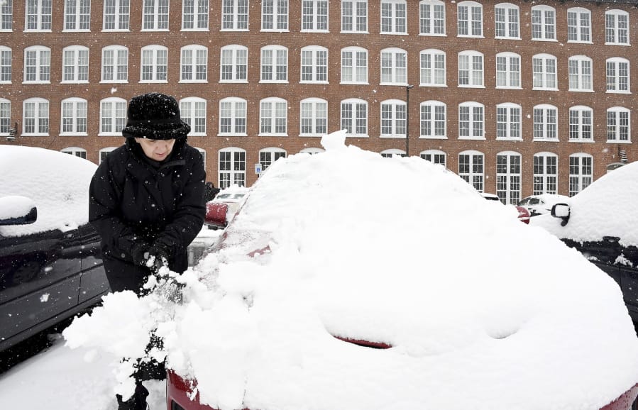 Sue Baker clears snow from her car at the Sterling Lofts apartments Tuesday in Attleboro, Mass.