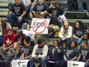 Spectators at Hudson&#039;s Bay on Friday hold signs and wear T-shirts protesting against racial taunts basketball players say they received at a game earlier this season in Kelso.
