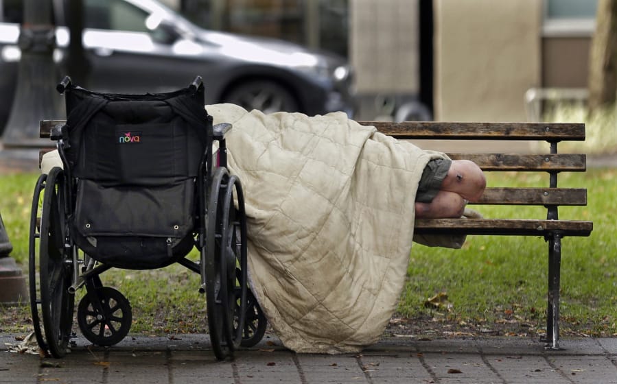 A person sleeps next to a wheelchair on a park bench in downtown Portland on Sept. 19, 2017, not far from the city&#039;s trendy Pearl District.  A Wednesday Oregon Court of Appeals ruling raised questions about Portland&#039;s camping ban. (Ted S.