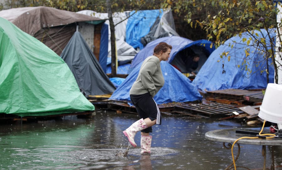 Crystal Claflin wades past tents and through water in Nickelsville, a homeless encampment in Seattle in 2012 after a storm.