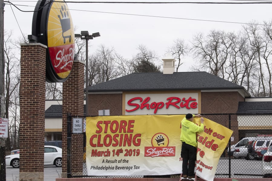 A worker places a store closing sign at the ShopRite on Haverford Avenue in Philadelphia in January 2019. The sign declares that the store&#039;s closing is &quot;a result of the Philadelphia Beverage Tax.&quot; (Jose F.
