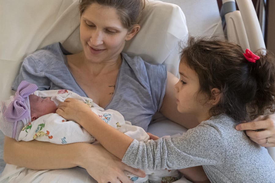 Tia Purviance holds her newborn daughter, Evaine Josephina, while sister Allie leans in to see the new baby. Evaine was the first baby born in Clark County in 2020, entering the world at 4:41 a.m. at PeaceHealth Southwest Medical Center&#039;s Family Birth Center.