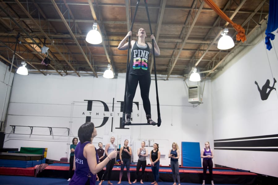 Kelley Baker stands on top of the bar during a Saturday adult trapeze class by Premier Cirque in Hazel Dell.