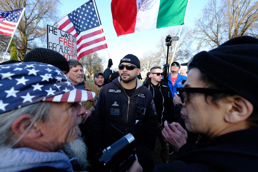 Patriot Prayer leader Joey Gibson, center, leads a protest in Portland in December 2017, a week after an undocumented Mexican resident of San Francisco was acquitted of the murder of Kate Seinle. It drew activists from both political extremes, including Kerry Hudson, left, who can be found at many Patriot Prayer rallies and Luis Enrique Marquez, right, a prominent anti-fascist protester.