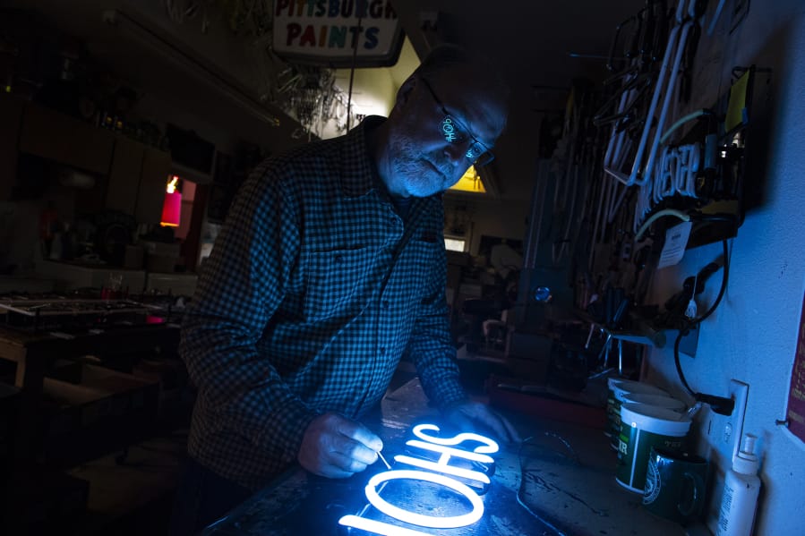 Roger Schurman, owner of Gas &#039;n Glass, applies touch-up paint to a barber shop&#039;s neon sign at his workshop in Ridgefield.