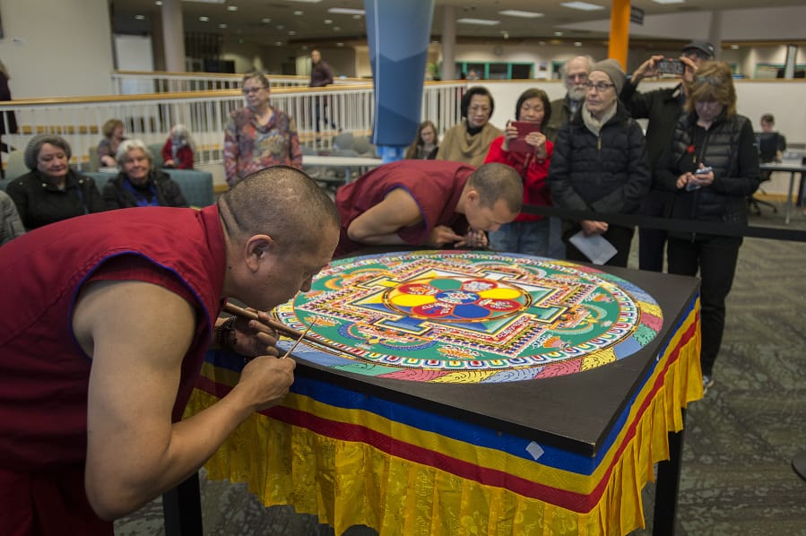 LEADOPTION
Jampa Tenzin, left, and Ngawang Shakya, Tibetan Buddihist monks, attract a crowd while adding the finishing touches to a sand mandala at Clark College on Friday afternoon.  According to Tibetan Buddhist belief, a sand mandala is meant to create a profound experience of compassion for any who attend. (Amanda Cowan/The Columbian)