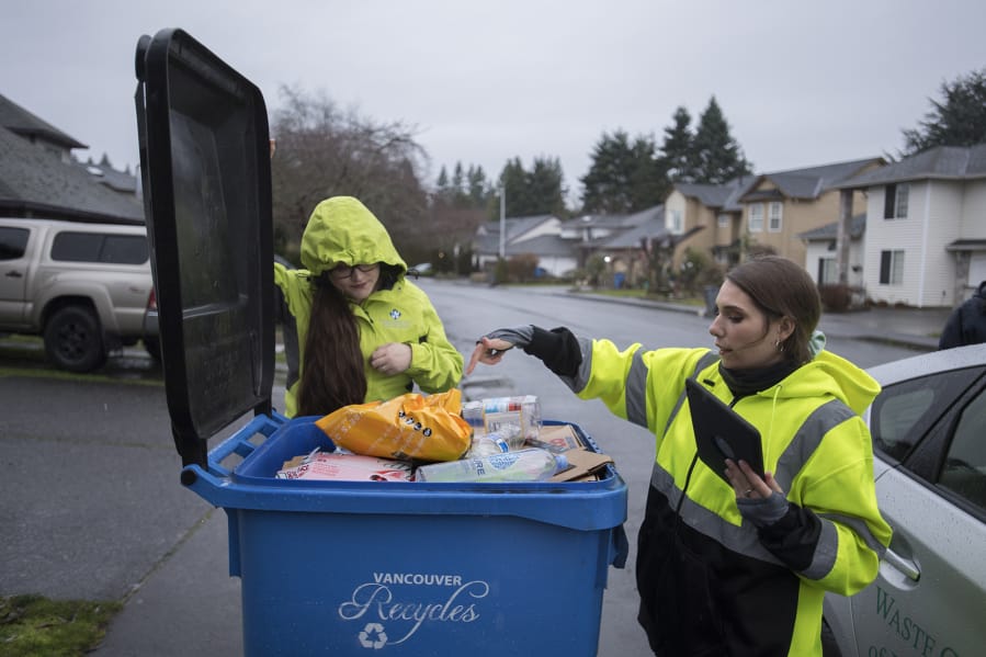 Gina Evans, left, and Jerin Dinkins, recycling specialists with Waste Connections of Washington, look for items that cannot be recycled Thursday morning in Vancouver&#039;s Burton-Evergreen neighborhood.