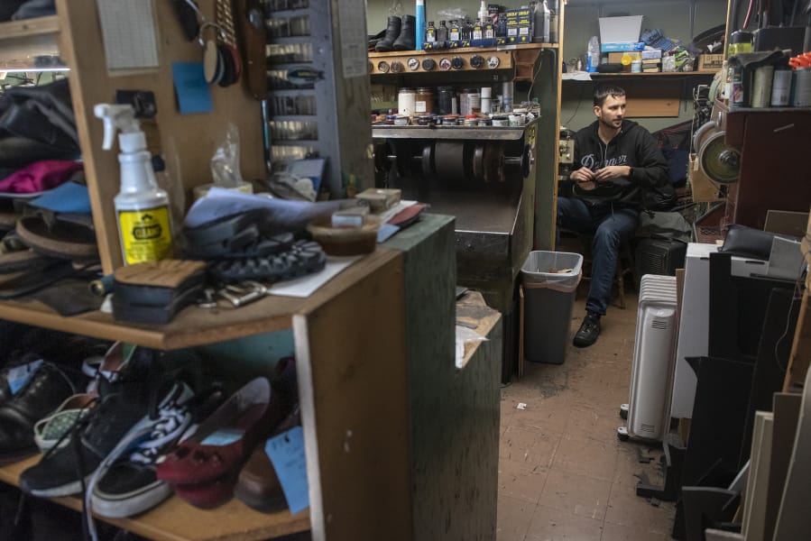 Vitaliy Gerasimov, owner of Totem Shoe Repair, works on the stitching for a pair of sneakers.