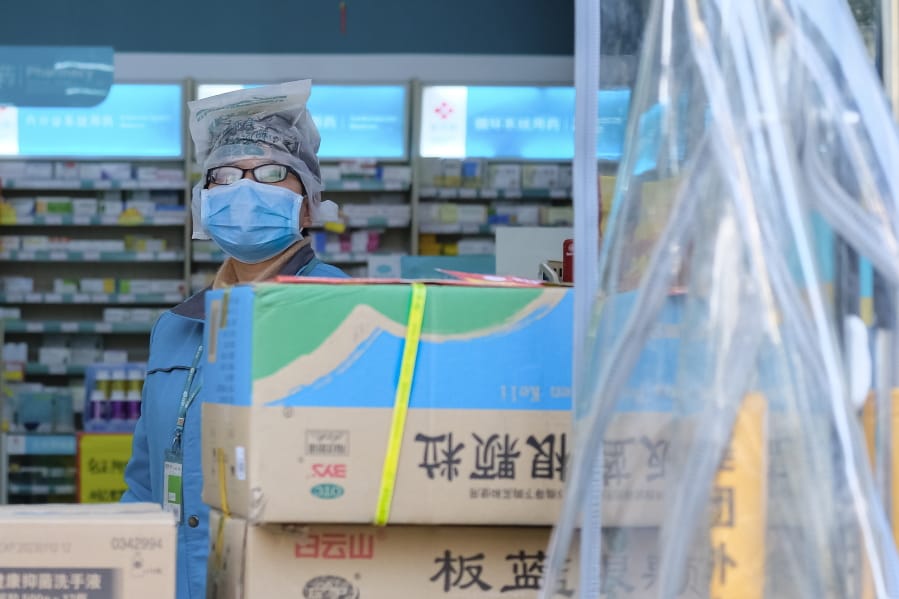 A clerk wearing a face mask and a plastic bag stands in a pharmacy in Wuhan in central China&#039;s Hubei Province, Friday, Jan. 31, 2020. The U.S. advised against all travel to China as the number of cases of a worrying new virus spiked more than tenfold in a week, including the highest death toll in a 24-hour period reported Friday.