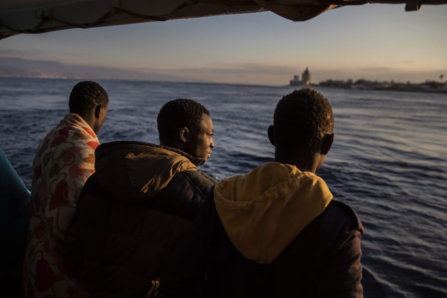 Men who were rescued off the Libyan coast on Friday, watch the city of Messina from the deck of the Open Arms rescue vessel as the ship enters the port located on the island of Sicily, Italy, Wednesday, Jan. 15, 2020.