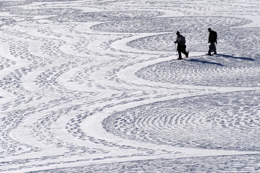 British artist Simon Beck, left, and a volunteer put the final touches on a geometrical snow drawing Jan. 7 on a frozen reservoir near Silverthorne, Colo. Beck says he hopes his art makes people more aware of the beauty of the environment.