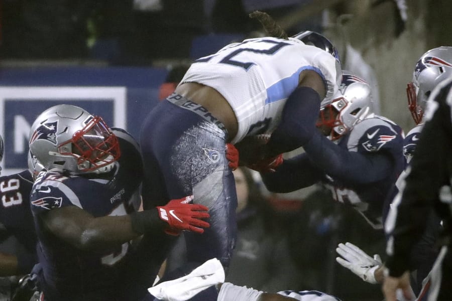 Tennessee Titans running back Derrick Henry runs from New England Patriots defenders in the first half of an NFL wild-card playoff football game, Saturday, Jan. 4, 2020, in Foxborough, Mass.
