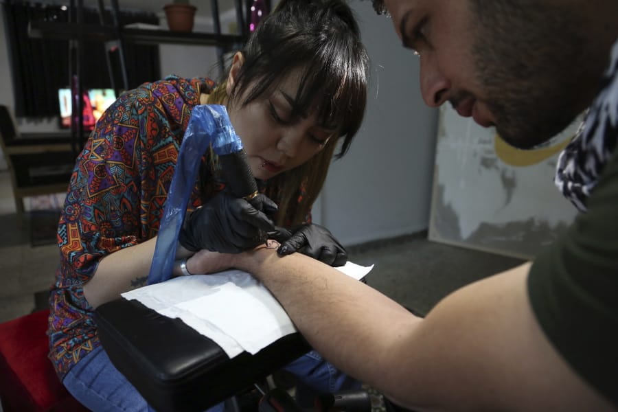 Tattoo artist Suraya Shaheedi, 26, left, does her art on a male customer in Kabul, Afghanistan. It&#039;s been 18 months since Shaheedi started her mobile tattoo shop in the capital city. She&#039;s received death threats for taking on the taboo of the ink-on-skin drawings she does -- as well as being a single woman willing to work with men..