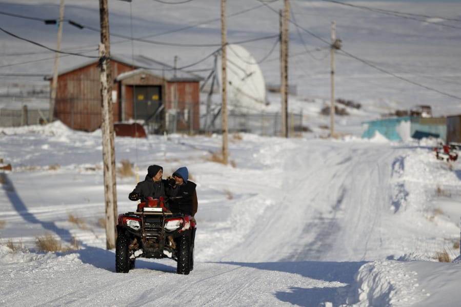 People ride through town on all-terrain vehicles Saturday, Jan. 18, 2020, in Toksook Bay, Alaska. The first Americans to be counted in the 2020 Census starting Tuesday, Jan. 21, live in this Bering Sea coastal village. The Census traditionally begins earlier in Alaska than the rest of the nation because frozen ground allows easier access for Census workers, and rural Alaska will scatter with the spring thaw to traditional hunting and fishing grounds.