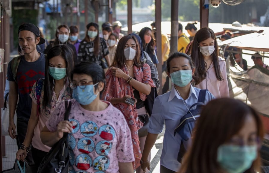 Boat passengers on a jetty wear face masks in Bangkok, Thailand, Tuesday, Jan. 28, 2020 to protect themselves from new virus infection. Panic and pollution drive the market for protective face masks, so business is booming in Asia, where fear of the coronavirus from China is straining supplies and helping make mask-wearing the new normal.