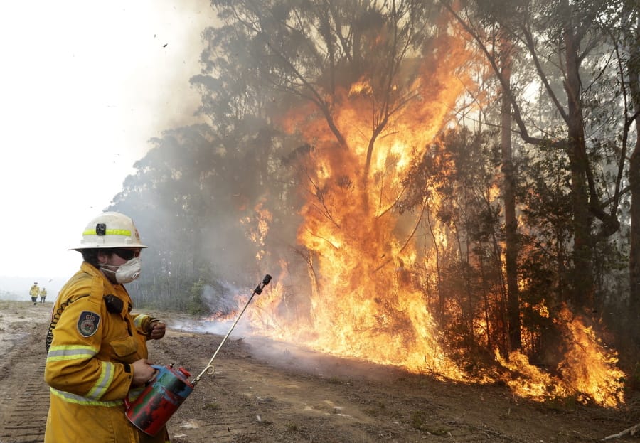 A firefighters backs away from the flames Wednesday after lighting a controlled burn near Tomerong, Australia, in an effort to contain a larger fire nearby.