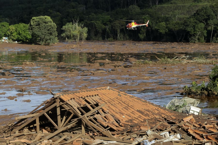 FILE - In this Sunday, Jan. 27, 2019 file photo, rescue workers in a helicopter search a flooded area after a dam collapsed in Brumadinho, Brazil. Prosecutors in the Brazilian state of Minas Gerais said Tuesday, Jan. 21, 2020 they will present charges against mining giant Vale, its German auditor Tuv Sud and 16 individuals in connection with the dam collapse last January that killed more than 200 people.