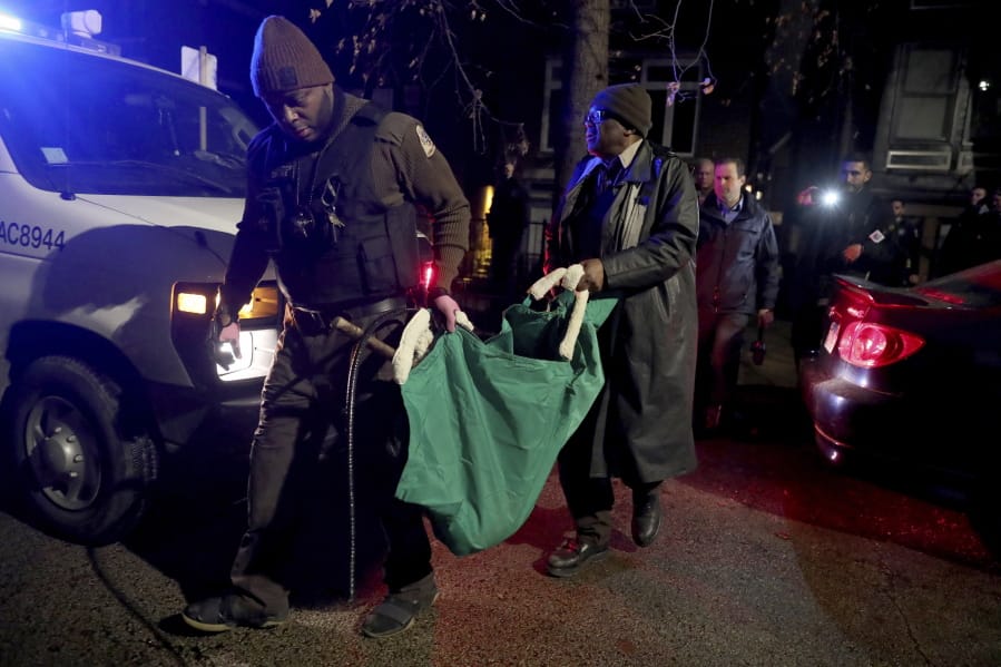 A Chicago police officer and a Chicago Animal Care and Control worker carry a coyote out in a green bag after tranquilizing the animal behind a home on Thursday, Jan. 9, 2020.