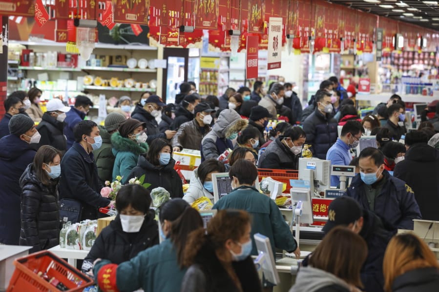 Shoppers wearing face masks pay for their groceries at a supermarket in Wuhan in central China&#039;s Hubei province, Saturday, Jan. 25, 2020. The virus-hit Chinese city of Wuhan, already on lockdown, banned most vehicle use downtown and Hong Kong said it would close schools for two weeks as authorities scrambled Saturday to stop the spread of an illness that is known to have infected more than 1,200 people and killed 41, according to officials.