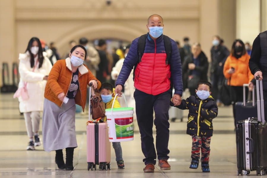 In this photo taken Tuesday, Jan. 21, 2020, travelers wearing face masks walk with their luggage at Hankou Railway Station in Wuhan in southern China&#039;s Hubei province. The U.S. on Tuesday reported its first case of a new and potentially deadly virus circulating in China, saying a Washington state resident who returned last week from the outbreak&#039;s epicenter was hospitalized near Seattle.