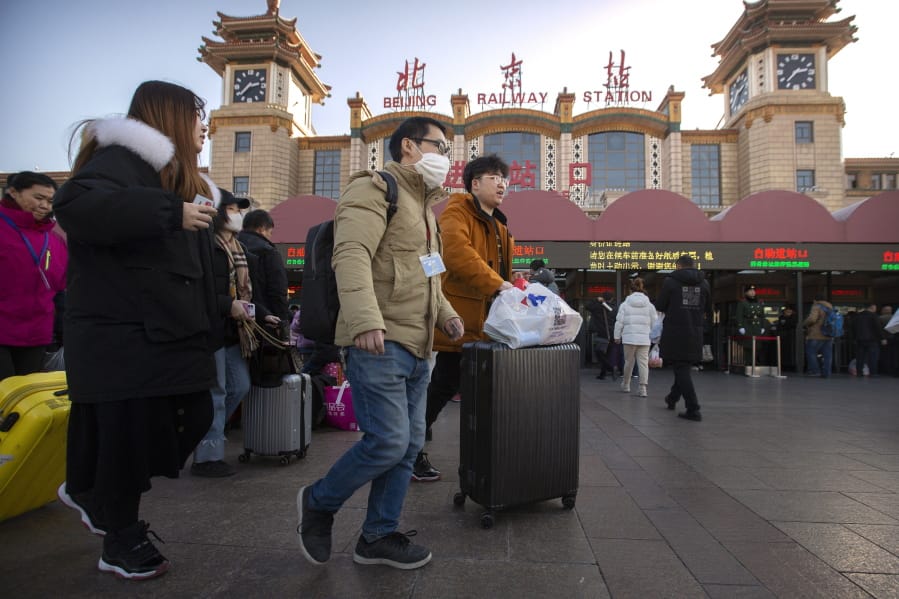 A traveler wears a face mask as he walks outside of the Beijing Railway Station in Beijing, Monday, Jan. 20, 2020. China reported Monday a sharp rise in the number of people infected with a new coronavirus, including the first cases in the capital. The outbreak coincides with the country&#039;s busiest travel period, as millions board trains and planes for the Lunar New Year holidays.