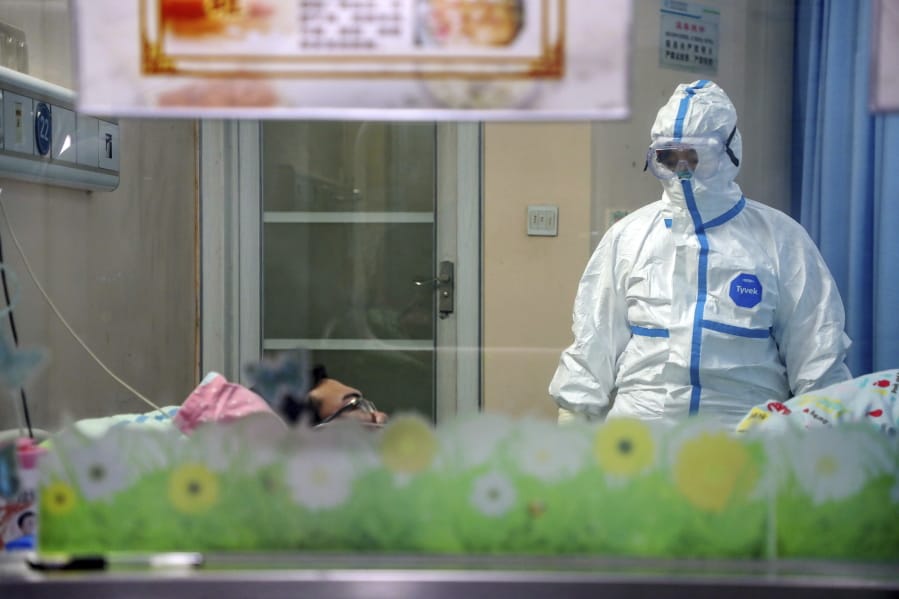 A doctor attends to a patient in an isolation ward at a hospital in Wuhan in central China&#039;s Hubei Province, Thursday, Jan. 30, 2020. China counted 170 deaths from a new virus Thursday and more countries reported infections, including some spread locally, as foreign evacuees from China&#039;s worst-hit region returned home to medical observation and even isolation.