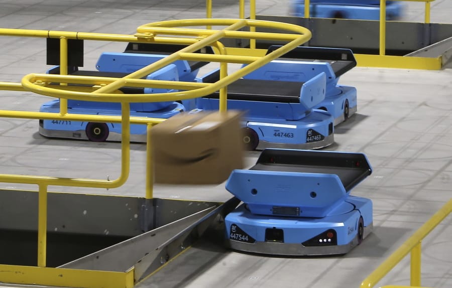 FILE - In this Dec. 17, 2019, file photo an Amazon robot sends a package down a chute, transporting packages from workers to chutes that are organized by zip code, at an Amazon warehouse facility in Goodyear, Ariz. Amazon.com reports financial results on Thursday, Jan. 30, 2020. (AP Photo/Ross D.